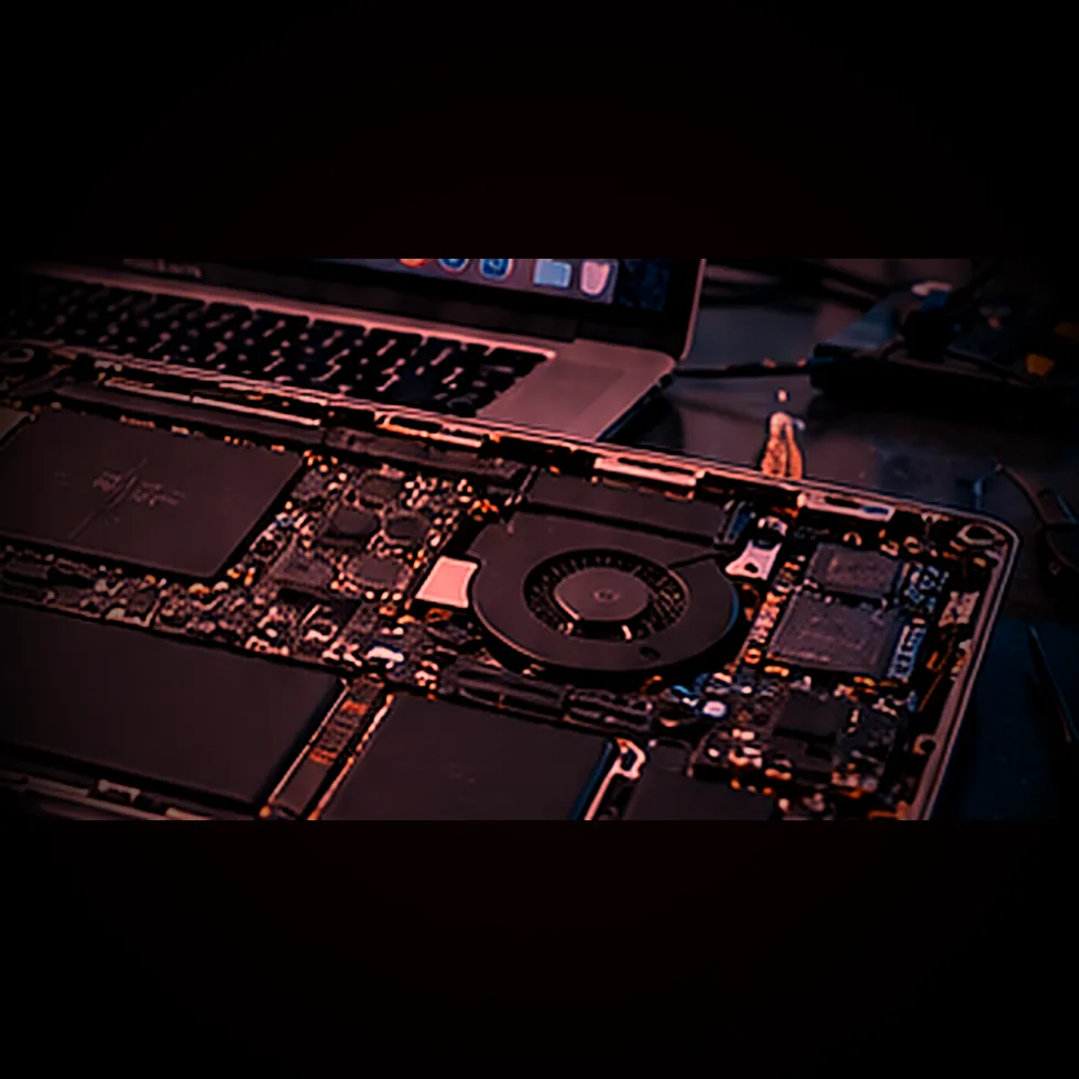 Placa base de un MacBook desmontada sobre la mesa del laboratorio con iluminación roja de advertencia